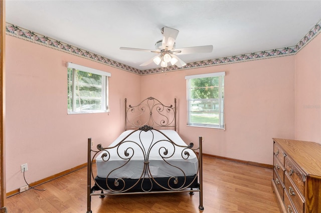 bedroom with ceiling fan, light wood-type flooring, and multiple windows