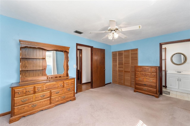 carpeted bedroom with ceiling fan, a closet, connected bathroom, and sink