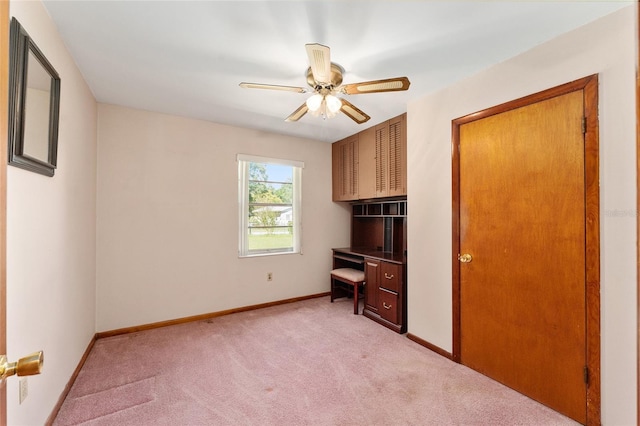 interior space with light carpet, built in desk, and ceiling fan