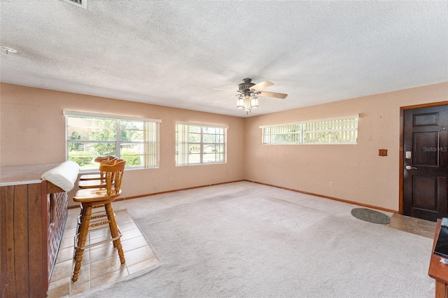 interior space with ceiling fan, a textured ceiling, and light carpet