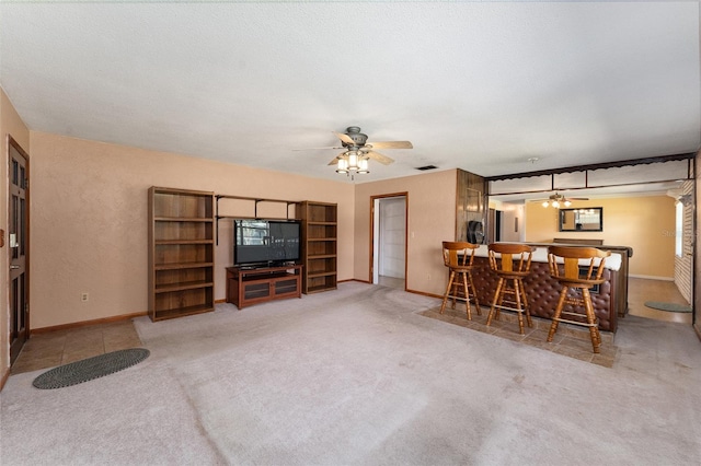 living room featuring ceiling fan, carpet floors, bar area, and a textured ceiling