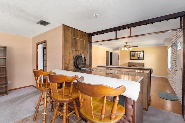 kitchen featuring light wood-type flooring, kitchen peninsula, ceiling fan, and a textured ceiling