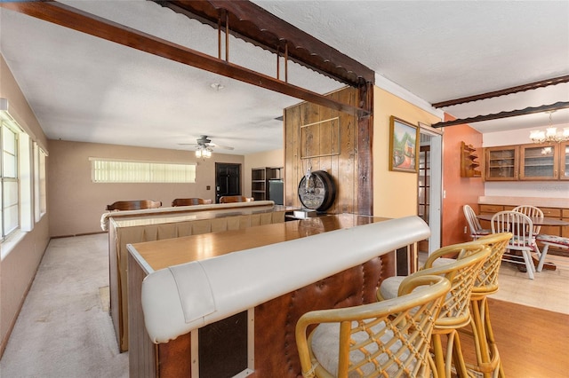 kitchen featuring a textured ceiling, ceiling fan with notable chandelier, and light colored carpet