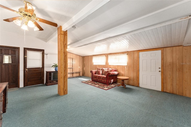 living room featuring vaulted ceiling with beams, ceiling fan, wood walls, and carpet flooring