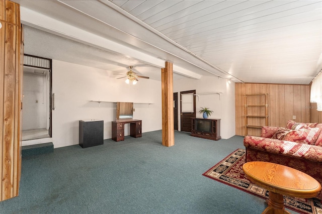 living room featuring ceiling fan, wooden walls, and dark colored carpet