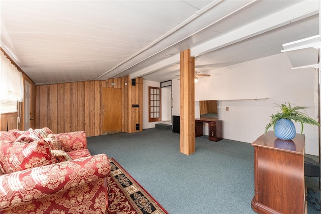 living room featuring carpet floors, wooden walls, ceiling fan, and beamed ceiling