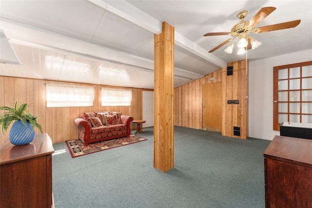 carpeted living room with wooden walls, lofted ceiling with beams, and ceiling fan