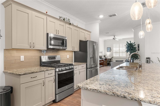 kitchen featuring hanging light fixtures, stainless steel appliances, light hardwood / wood-style flooring, ornamental molding, and sink