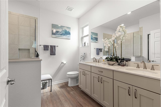 bathroom with a tile shower, toilet, vanity, and hardwood / wood-style floors