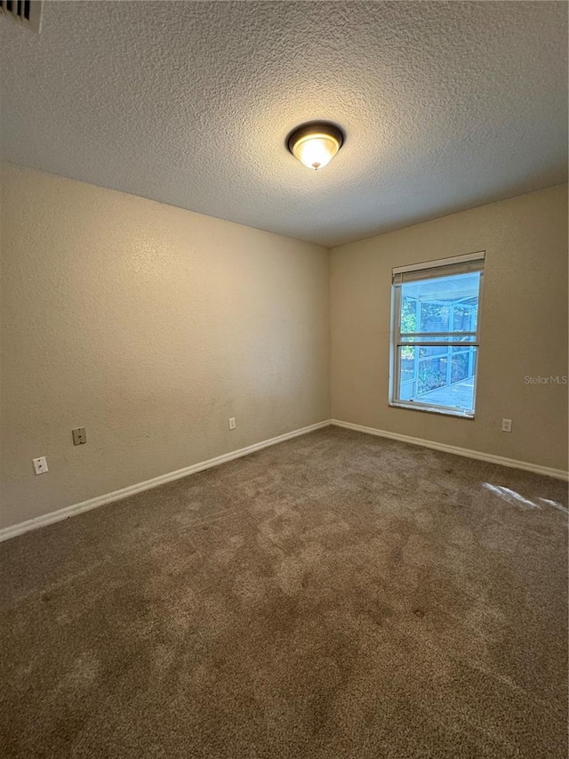 unfurnished room featuring dark carpet and a textured ceiling