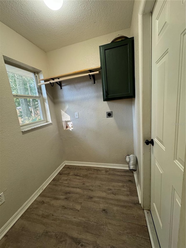 clothes washing area featuring hookup for an electric dryer, a textured ceiling, cabinets, and dark wood-type flooring