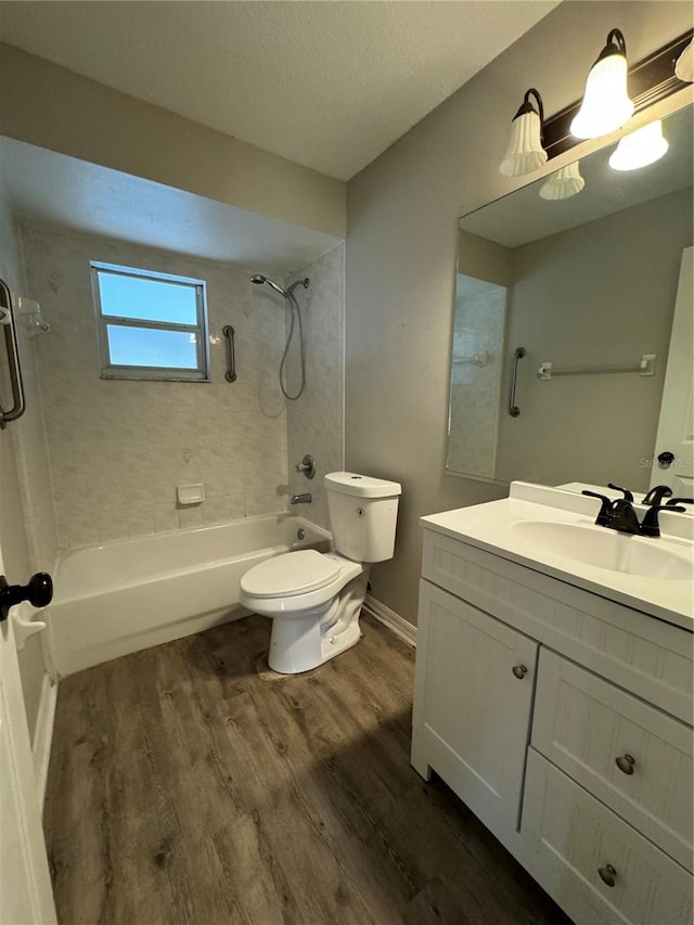 full bathroom featuring tiled shower / bath combo, hardwood / wood-style floors, a textured ceiling, toilet, and vanity