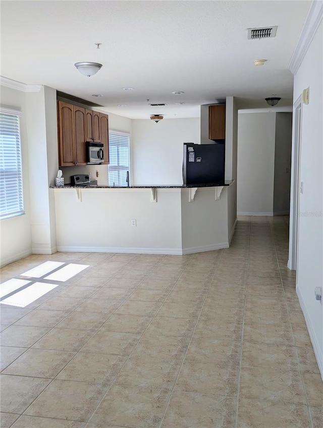 kitchen featuring refrigerator, ornamental molding, a wealth of natural light, and kitchen peninsula