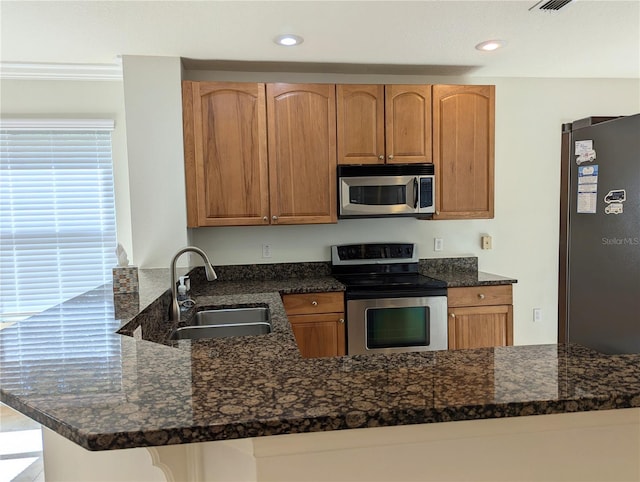 kitchen featuring dark stone counters, appliances with stainless steel finishes, sink, and kitchen peninsula