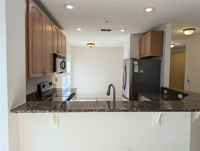 kitchen with sink, a breakfast bar, appliances with stainless steel finishes, and kitchen peninsula