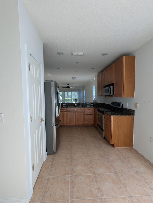 kitchen with stainless steel appliances, sink, light tile patterned flooring, a textured ceiling, and ceiling fan