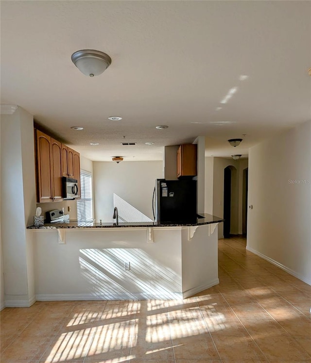 kitchen with stainless steel appliances, stone countertops, and a breakfast bar area