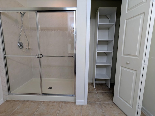 bathroom with a shower with door and tile patterned flooring