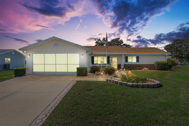 ranch-style home featuring a garage, a yard, and central AC