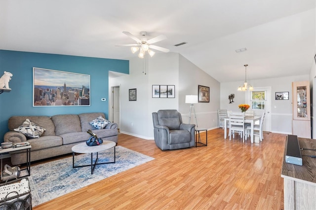 living room with ceiling fan with notable chandelier, light hardwood / wood-style floors, and vaulted ceiling