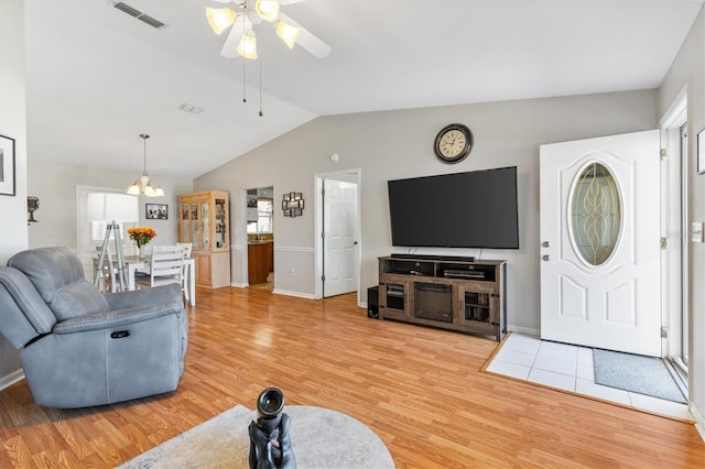 living room featuring wood-type flooring, ceiling fan with notable chandelier, plenty of natural light, and vaulted ceiling