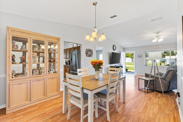 dining area featuring lofted ceiling, ceiling fan with notable chandelier, and light wood-type flooring