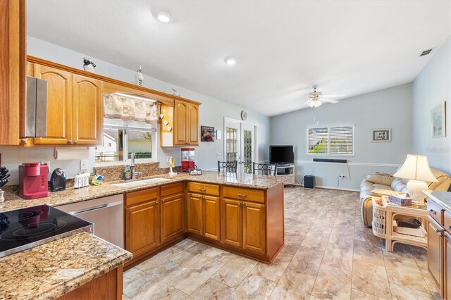 kitchen with ceiling fan, lofted ceiling, sink, kitchen peninsula, and light stone countertops