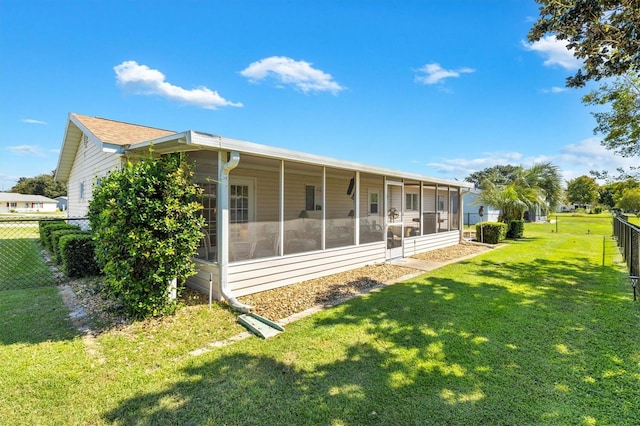 rear view of property with a yard and a sunroom