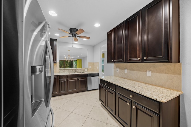 kitchen with stainless steel appliances, light stone counters, hanging light fixtures, and sink