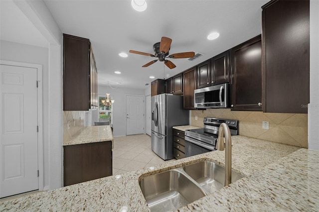 kitchen featuring decorative backsplash, light stone countertops, stainless steel appliances, ceiling fan, and sink