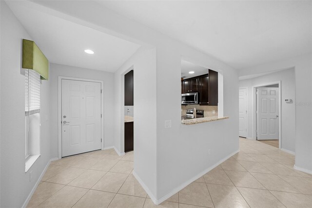 interior space with dark brown cabinets, decorative backsplash, appliances with stainless steel finishes, and light tile patterned floors