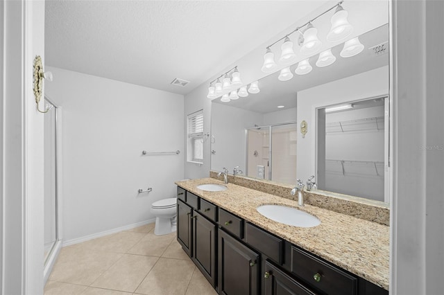 bathroom with vanity, tile patterned flooring, a textured ceiling, a shower with shower door, and toilet