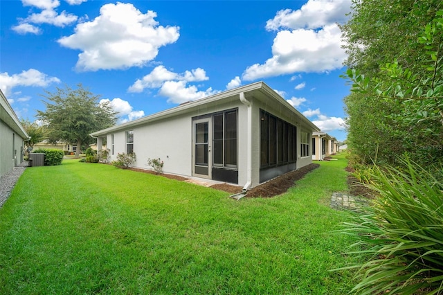 rear view of property featuring a sunroom, central air condition unit, and a yard