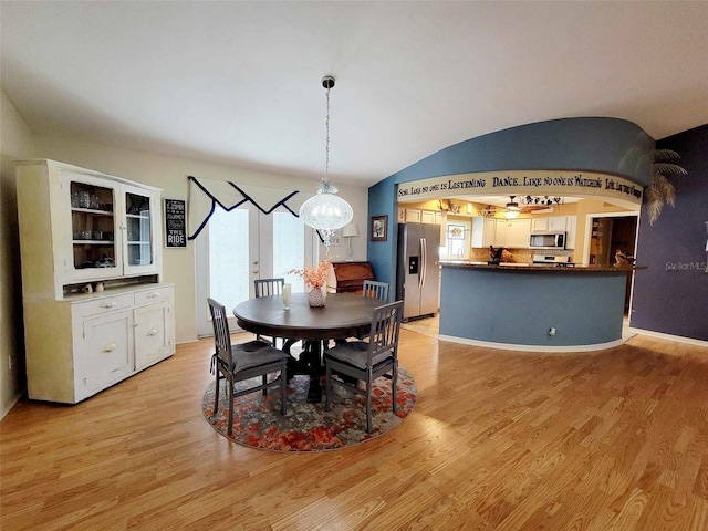 dining area with light wood-type flooring and lofted ceiling