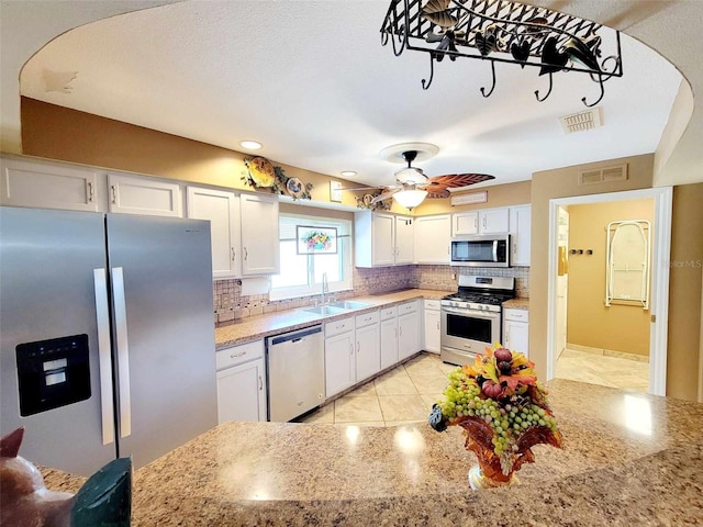 kitchen featuring ceiling fan, white cabinets, sink, appliances with stainless steel finishes, and light stone countertops