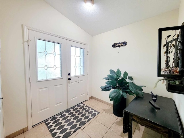 foyer with french doors, vaulted ceiling, light tile patterned floors, and a textured ceiling