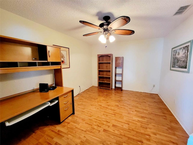 home office with light wood-type flooring, ceiling fan, and a textured ceiling