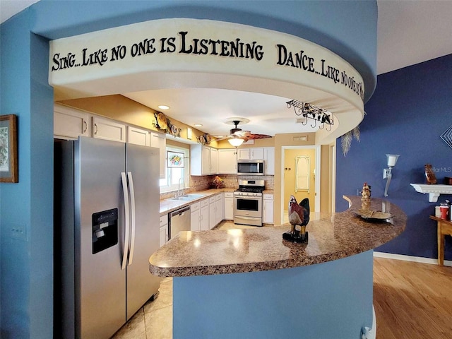 kitchen with light wood-type flooring, sink, stainless steel appliances, and white cabinets