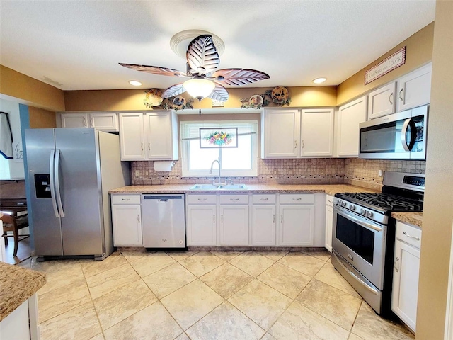 kitchen featuring ceiling fan, sink, white cabinetry, appliances with stainless steel finishes, and backsplash