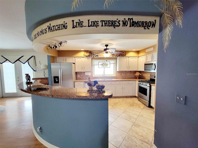 kitchen with ceiling fan, light hardwood / wood-style flooring, backsplash, white cabinets, and appliances with stainless steel finishes