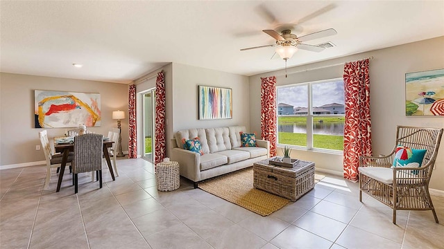 living room featuring ceiling fan, light tile patterned floors, and a water view