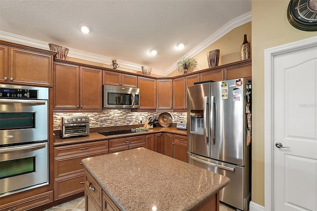 kitchen featuring light stone counters, lofted ceiling, backsplash, appliances with stainless steel finishes, and crown molding