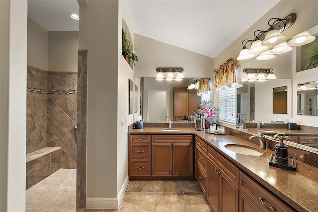 bathroom featuring vaulted ceiling, vanity, tile patterned flooring, and a tile shower