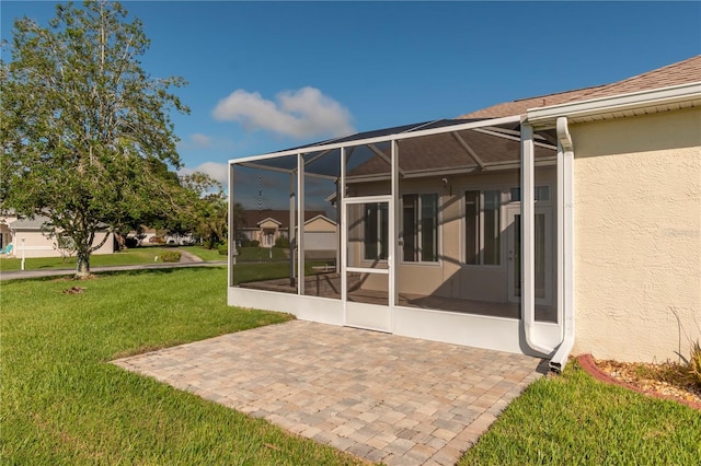 rear view of property with a lawn, a lanai, and a patio