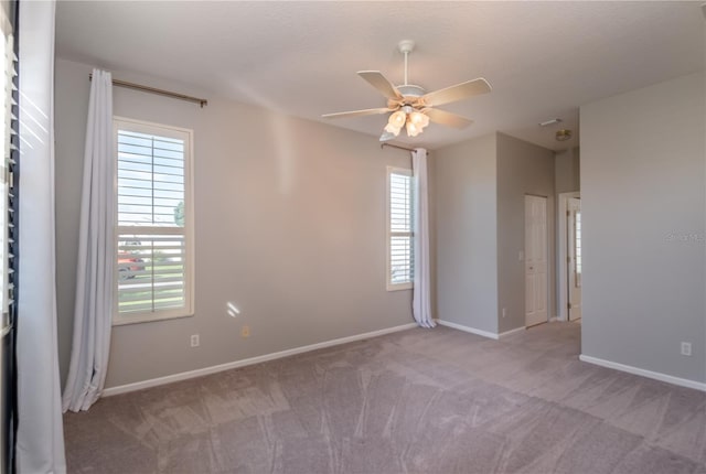 empty room with a textured ceiling, a healthy amount of sunlight, ceiling fan, and light carpet