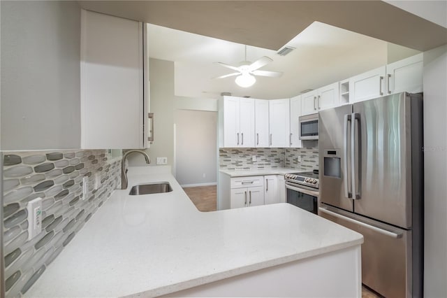 kitchen featuring appliances with stainless steel finishes, kitchen peninsula, white cabinets, and tasteful backsplash