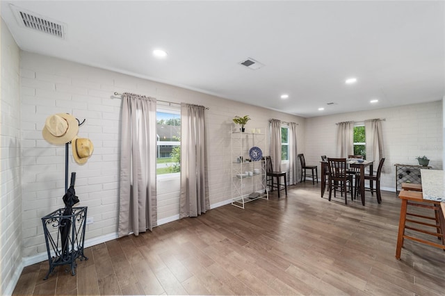 dining space with wood-type flooring and brick wall