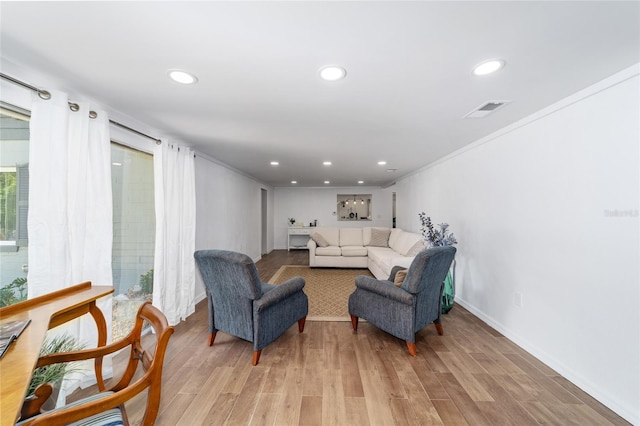 living room with ornamental molding and light hardwood / wood-style floors