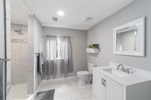 bathroom featuring vanity, tile patterned flooring, toilet, and tiled shower