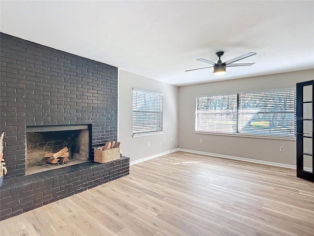 unfurnished living room with ceiling fan, a fireplace, and light hardwood / wood-style floors